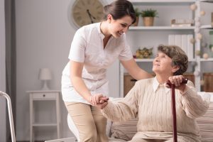 Young carer supporting senior disabled woman with walking stick.